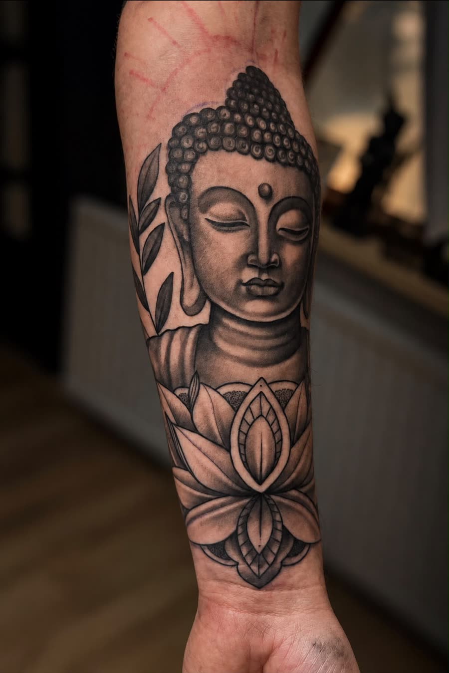 Buddha-Kopf mit Lotusblüte am Unterarm, Schwarz-Grau – Tattoo aus Bad Bramstedt
